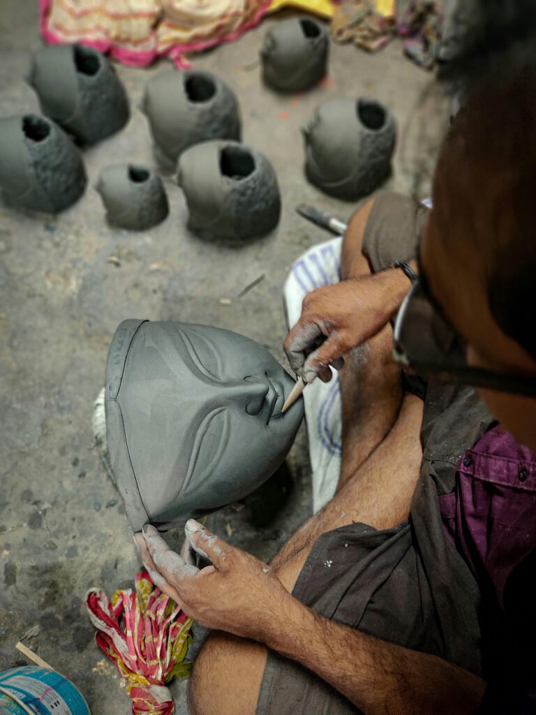 A man sculpting a clay mask with his hands, showcasing his artistic skills and creativity.