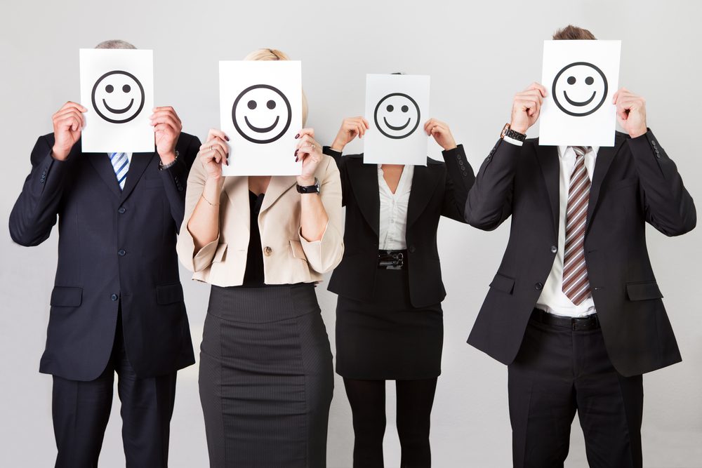 Group of professionals displaying smiley face cards in a meeting.
