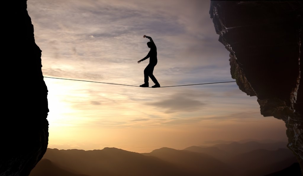 A man walking down the rope of life with dawn at background. Risk must be taken in order to achieve psychological safety & S.A.T.O.R.I. attitude